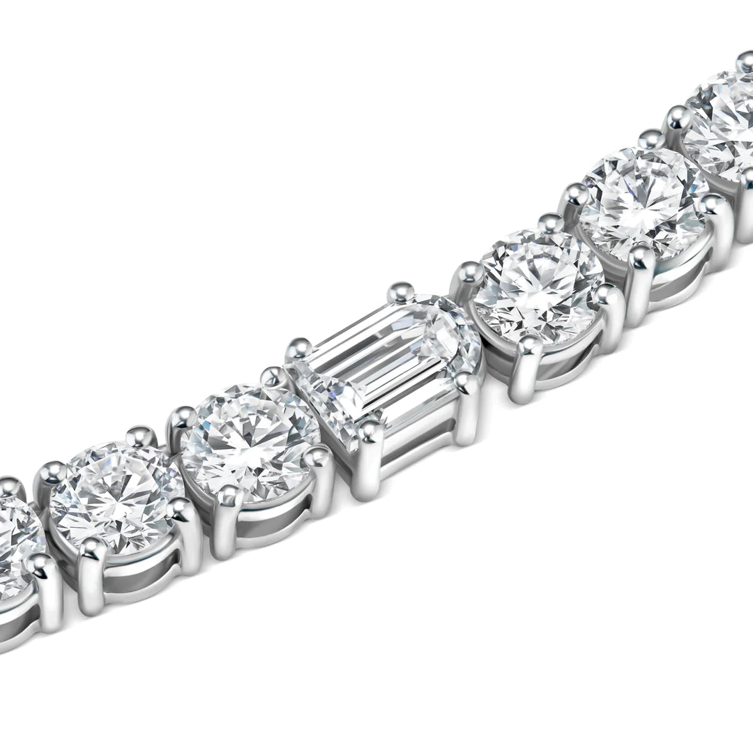 Close-up of a silver bracelet featuring round-cut diamonds and a single rectangular emerald-cut diamond set in a row, highlighting their sparkle and clarity.