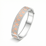 The L'Arc de DAVIDOR Bangle GM in Bellini, crafted from 18k white gold with pink lacquered ceramic and Palais Diamonds, features a wave design bordered by sparkling stones—photographed on a white background.