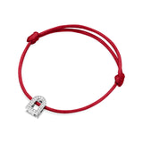 The L'Arc Voyage Charm PM bracelet, crafted from 18k white gold and adorned with Galerie diamonds, features a red silk cord that loops elegantly with a simple knot on each side. This minimalist design effortlessly captures the timeless sophistication of a Paris atelier.