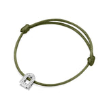 The L'Arc Voyage Charm PM is a silk cord bracelet in green, featuring an elegant 18k white gold lock-shaped charm adorned with Galerie diamonds. It is intricately crafted in the sophisticated Paris Atelier and secured with simple knots framing the charm.