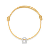 A L'Arc Voyage Charm PM, crafted from 18k white gold and adorned with Galerie diamonds, elegantly rests on a delicate yellow silk cord bracelet with an adjustable knot.