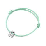 A silk cord bracelet in mint green showcases an 18k white gold L'Arc Voyage Charm embellished with Galerie diamonds. Crafted by Paris Atelier, it features adjustable knots on either side of the charm for a perfect fit.