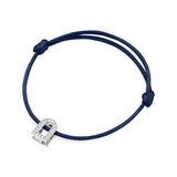 Introducing the L'Arc Voyage Charm PM, a silk cord bracelet in dark blue with an 18k white gold charm adorned with Galerie diamonds. Crafted in the Paris Atelier, this elegant piece features adjustable knots on each side of the charm for a secure fit.