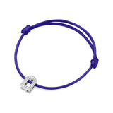 The L'Arc Voyage Charm PM bracelet showcases a vibrant purple silk cord with adjustable knots and features an 18k white gold charm shaped like a padlock, adorned with Galerie diamonds. Crafted with exquisite attention to detail, this piece mirrors the elegance of fine jewelry from a Paris atelier.