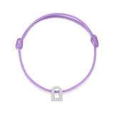 The L'Arc Voyage Charm PM bracelet is a purple braided silk cord accessory that features an 18k white gold charm adorned with Galerie diamonds, shaped like an archway. Lovingly crafted by Paris Atelier, the centrally placed charm nestles perfectly between adjustable knots for a customized fit, its elegant design standing out against a plain white background.