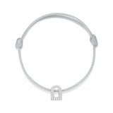 Introducing the L'Arc Voyage Charm PM bracelet: a minimalist piece designed with an adjustable thin gray silk cord and featuring an 18k white gold charm resembling a padlock, elegantly adorned with Galerie diamonds, inspired by the sophistication of Paris Atelier.