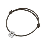 The L'Arc Voyage Charm PM bracelet features a sleek black silk cord with an 18k white gold lock charm adorned with Galerie diamonds. This chic accessory from the Paris Atelier is adjustable with knots on either side of the charm.