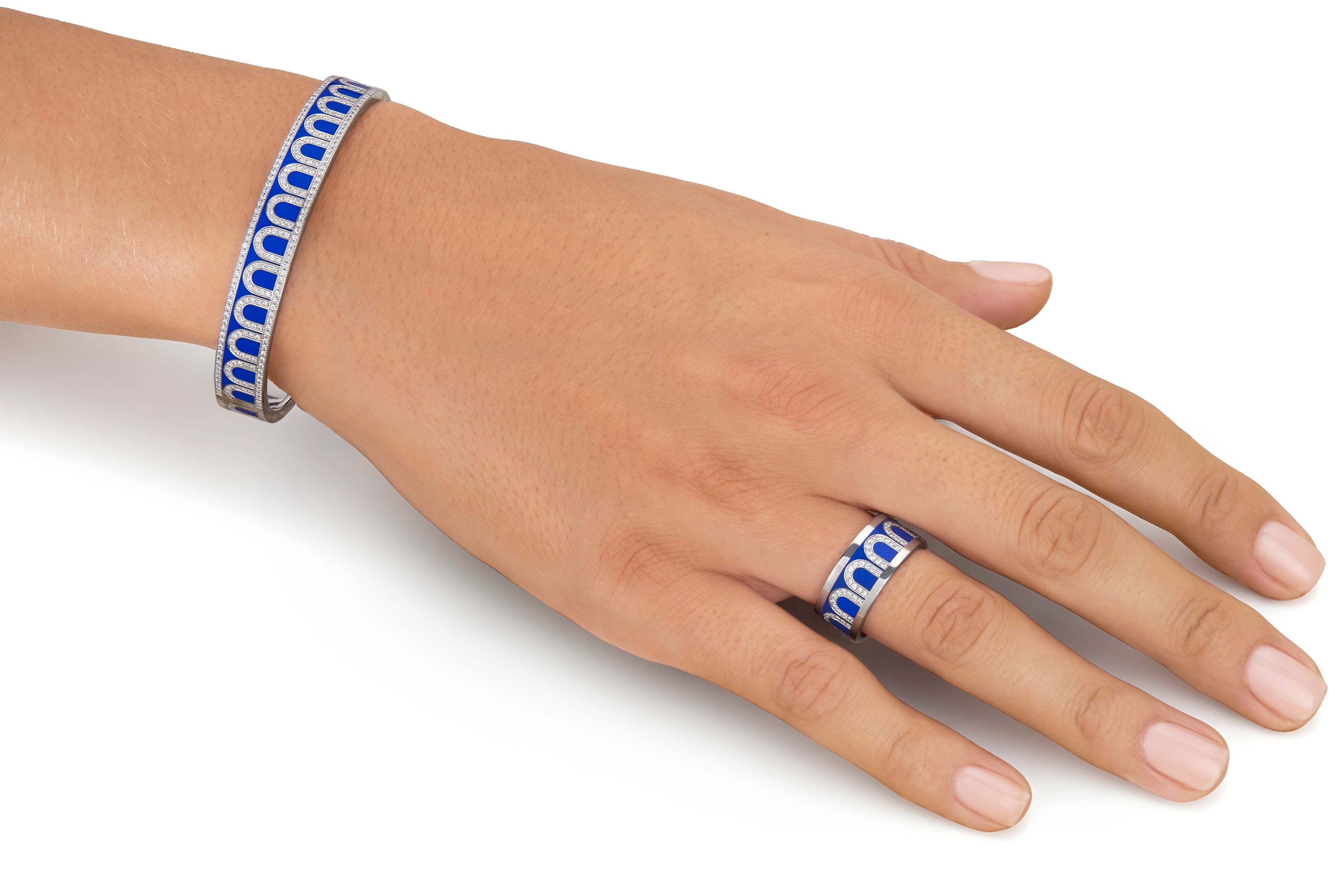 A hand wears the L'Arc de DAVIDOR Bangle MM in 18k white gold with lacquered ceramic and Palais Diamonds, paired with a matching ring, elegantly displayed on a white background.